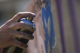 A man sprays graffiti on a wall with a spray can. Berlin, 14.08.2024