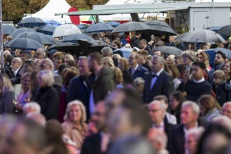 Guests stand under umbrellas at the Federal President's Citizens' Festival in Bellevue Palace