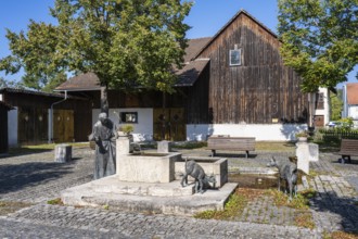 Town fountain with bronze sculptures by a stonemason and domestic goats in the town centre and old