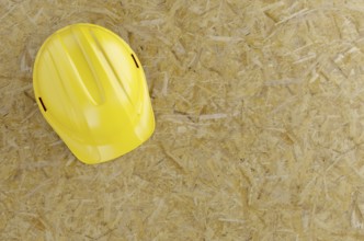 Overhead of yellow hard hat on particleboard with room for text