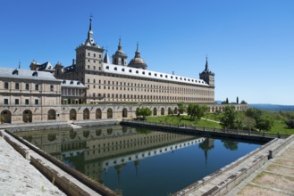 Historic monastery with reflection in the water trough under a blue sky, Real Sitio de San Lorenzo