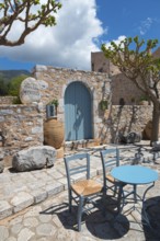 Inviting hotel terrace with stone walls and a blue sky with table and chairs in the shade,