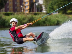 Boy or girl, water sports with wakeboard, red life jacket, water skiing in the wake park