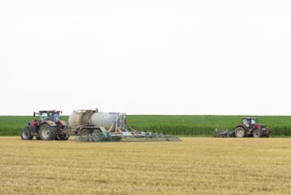 Farmers spread liquid manure on harvested grain field and plough it up, Swabian Alb,