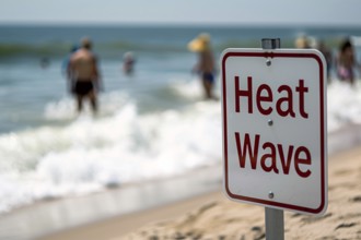 Sign with text 'Heat wave' in front of blurry sunny beach with people. KI generiert, generiert, AI