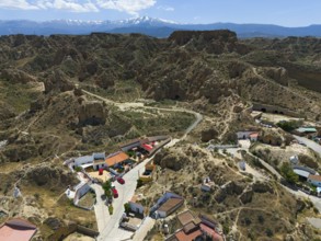 Mountain village with scattered houses and rocky landscape in the foreground, in a sunny valley