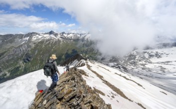 Mountaineer on a rocky ridge with snow, descent from the summit of Schönbichler Horn, view of