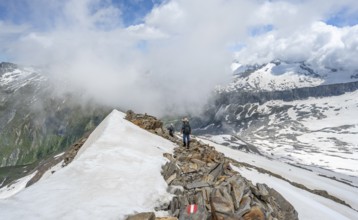 Mountaineer on a rocky ridge with snow, descent from the summit of Schönbichler Horn, view of