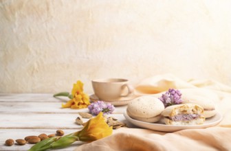 Meringues cakes with cup of coffee on a white background and orange linen textile. Side view, copy