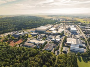 Industrial area surrounded by forest and landscape, numerous buildings and streets under a clear