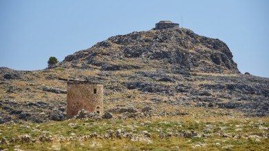 Medieval ruin in a rocky landscape with mountain in the background and clear sky, windmill, ruin,