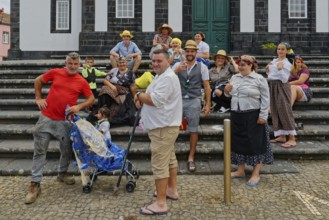 Group of cheerful people in traditional dress posing on a staircase, Fenais da Luz, Sao Miguel