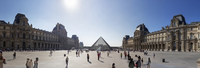 Panoramic view of the Louvre with the glass pyramid and numerous visitors under a clear sky, Paris