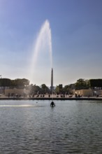 An impressive fountain in the sunlight, surrounded by people in a park, Paris