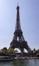 The mighty Eiffel Tower rises under a clear blue sky, close to the river, Paris