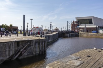 Waterfront promenade with people and modern building in the sunshine, Liverpool