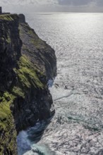 Sunbeams are reflected in the sea along the green cliffs that plunge into the depths, Cliffs of