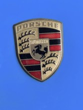 Historic old Porsche crest logo on blue painted bonnet of vintage classic car Porsche 911,