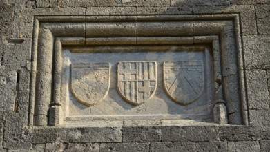 Stone relief with three coats of arms, moving in a rectangular frame on a historic wall, Knights'