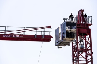 Erection of a construction crane, part of the upper crane section is hoisted by mobile crane onto