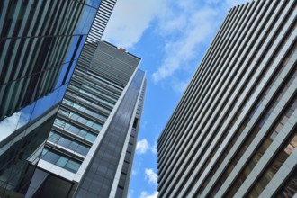 Tall modern skyscrapers with glass and steel facades against a bright blue sky with some clouds,