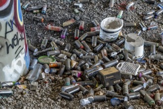 Empty spray paint cans, on a railway line below a road bridge, thrown away, disposed of by the