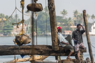 Fishermen resting, heavy stones attached to ropes, Chinese fishing nets, sunset, Arabian Sea coast,