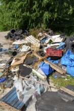 Illegally disposed waste, car tyres, building rubble, household waste, clothing, on a path next to