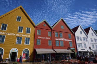 Traditional wooden houses under a blue sky with pitched roofs and multiple windows in a sunny old