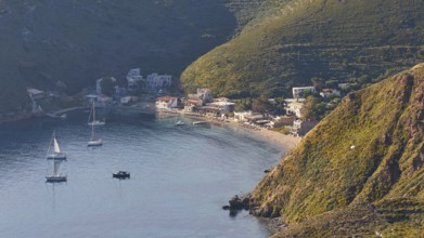 A picturesque coastal village with boats on a sunny evening, surrounded by mountains, southern tip,