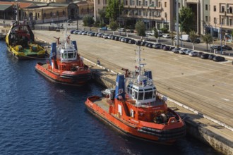 High angle view of docked orange, white and blue Capo D'Orlando and Megrez tugboats plus larger