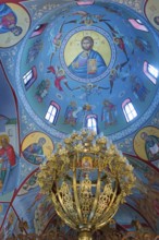 Religious icons and frescoes adorn a blue domed ceiling with a golden chandelier, Church of the