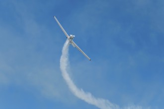 Stunt aerobatic plane performing stunts in blue sky with smoke trail. Concept of teamwork,