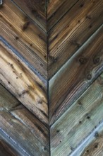 Close-up of of weathered pine wood planks assembled in V shaped patterns on exterior door, Quebec,