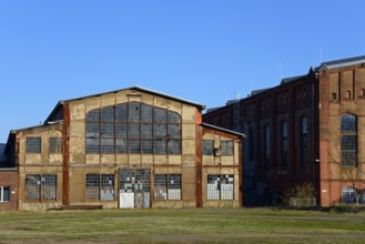 Abandoned industrial building with large windows and brick façade under a blue sky, Ilseder Hütte,