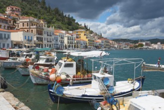 Historic coastal town with mooring boats on the water and colourful facades under a cloudy sky,