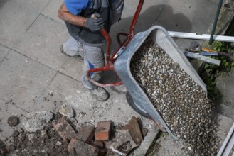 Construction worker empties wheelbarrow with gravel, Stuttgart, Baden-Württemberg