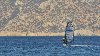 Windsurfer with view of rocky coast, clear blue water, windsurfer, Meltemi windsurfing area, Devils