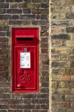 Red letterbox built into a brick wall, typical of urban England, Kew, London, England, Great