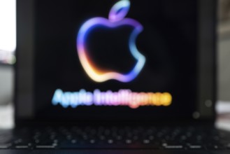 Blurred Apple Intelligence logo in bright neon colours on a Macbook with illuminated keyboard,