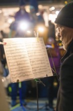 A musician on stage concentrates on his sheet music in the spotlight, Christmas market, Nagold,