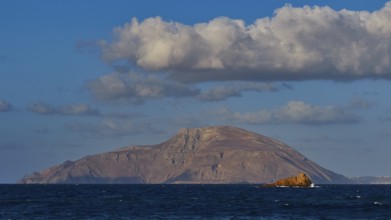 Island in the distance with rocks in the sea under blue sky, Arkasa, west coast, Kassos Island,