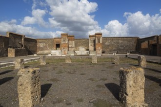 Remnants of old stone columns and terracotta brick and stone walls in a courtyard at the ancient