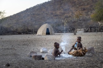 Himba children at an early morning fire, traditional Himba village, Kaokoveld, Kunene, Namibia,