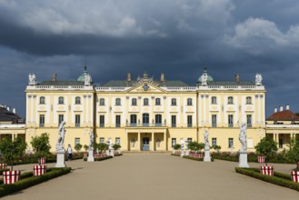 Yellow baroque castle with statues in the foreground and dramatic clouds, Branicki Palace, Castle,