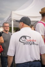 Security guard talking to festival visitors under a tent, Malleparty Böblingen, Germany, Europe