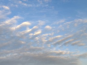 Diagonally arranged stratocumulus clouds are illuminated by warm sunlight at dusk, internationally