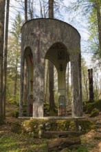 Round stone building in the forest with colonnades and works of art, Jama pod Krenom, commemoration