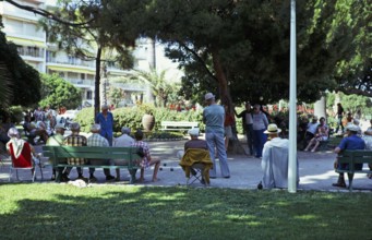 Men playing a game of boules in the shade of trees in a public park, Antibes, Côte d'Azur, France