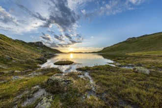 A calm lake with sunrise and cloud reflection, surrounded by mountains, Tyrol, Austria, Europe